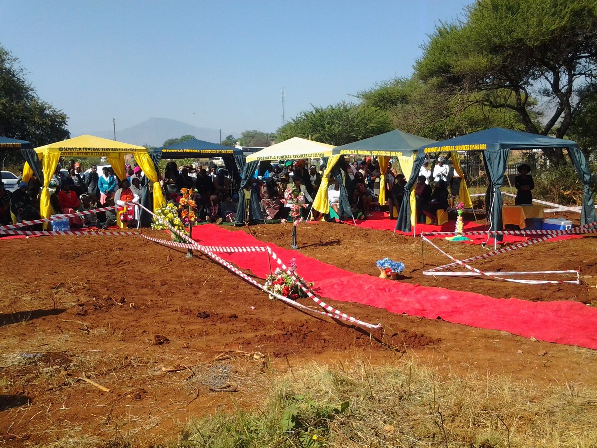 Graveside set up with red carpet, tents and decorations